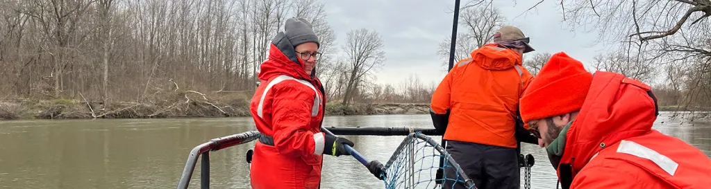 three people in a boat in orange jackets